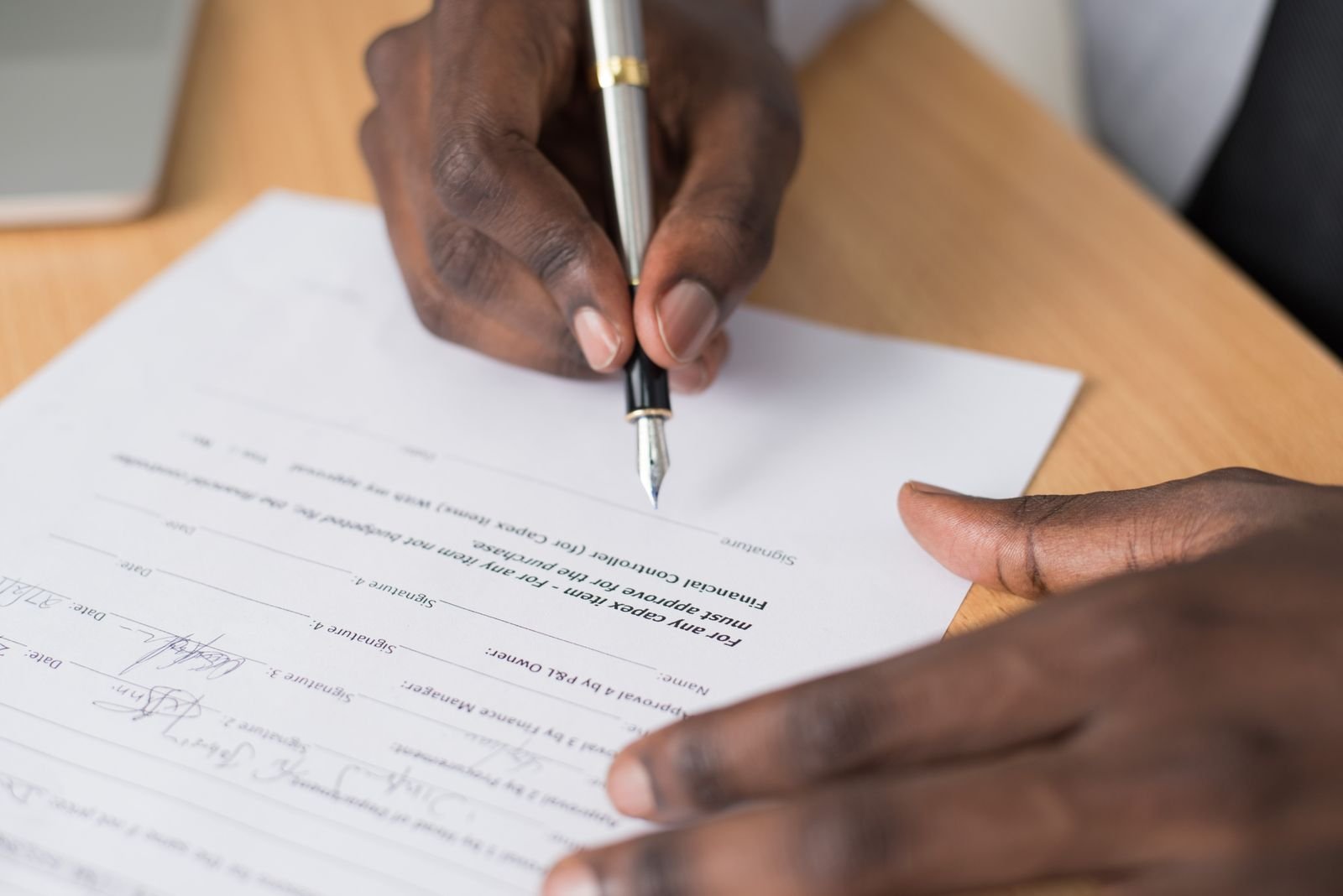 Close-up of hands signing a formal document indoors